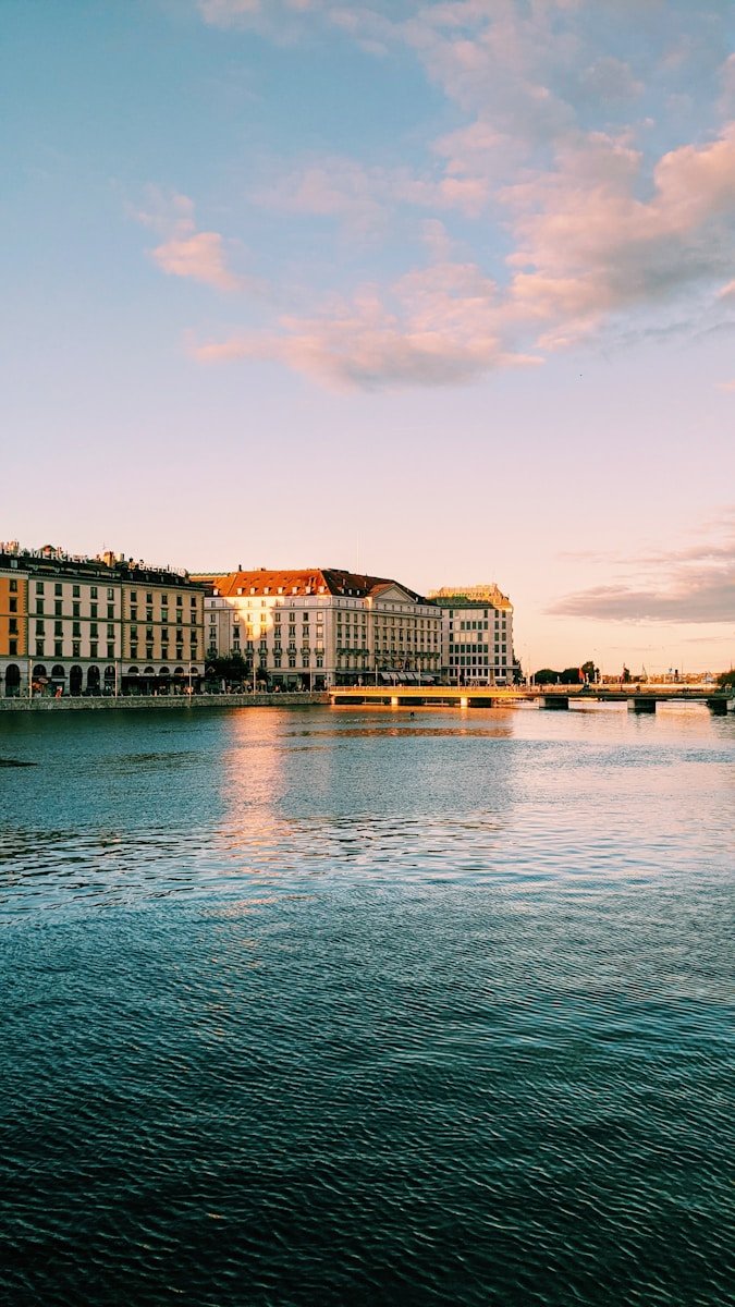 Buildings line the river under a colorful sky.