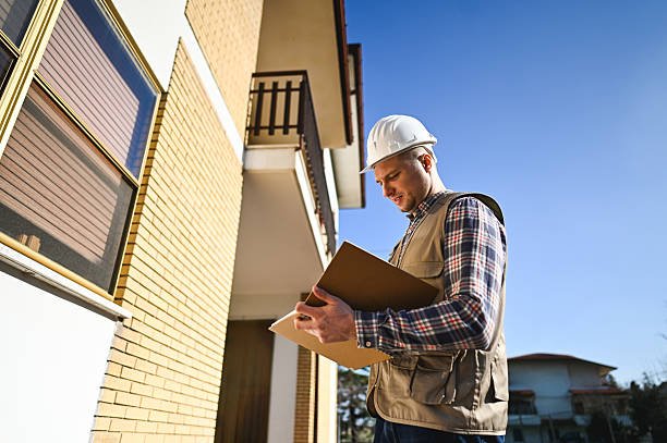 Building inspector examining documents outside residential building